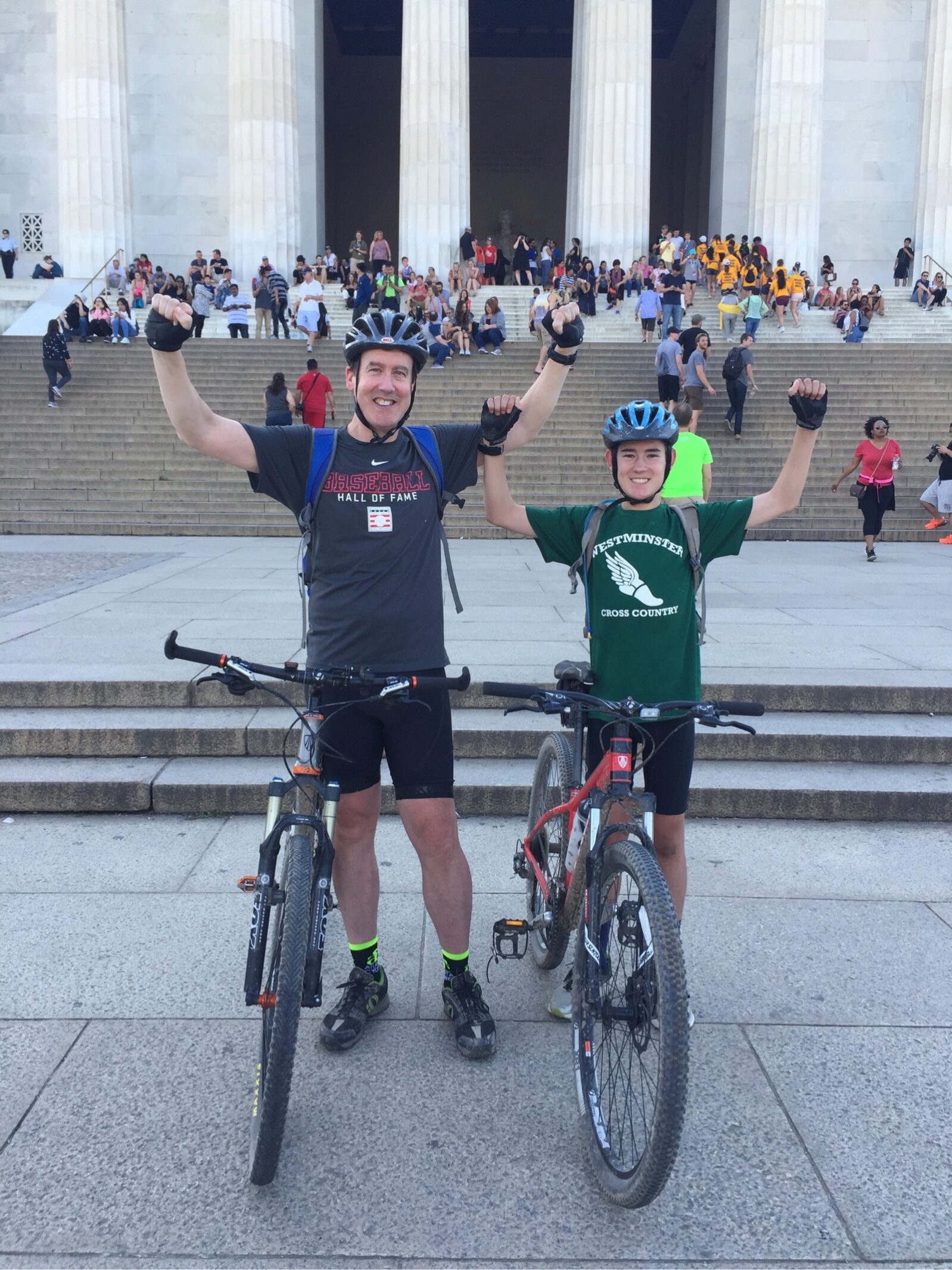 Two cyclists stand with their bikes in front of the Lincoln Memorial steps